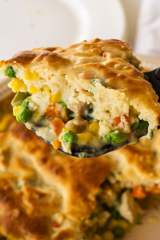 spatula serving pot pie out of dish, crispy and golden brown crust. 