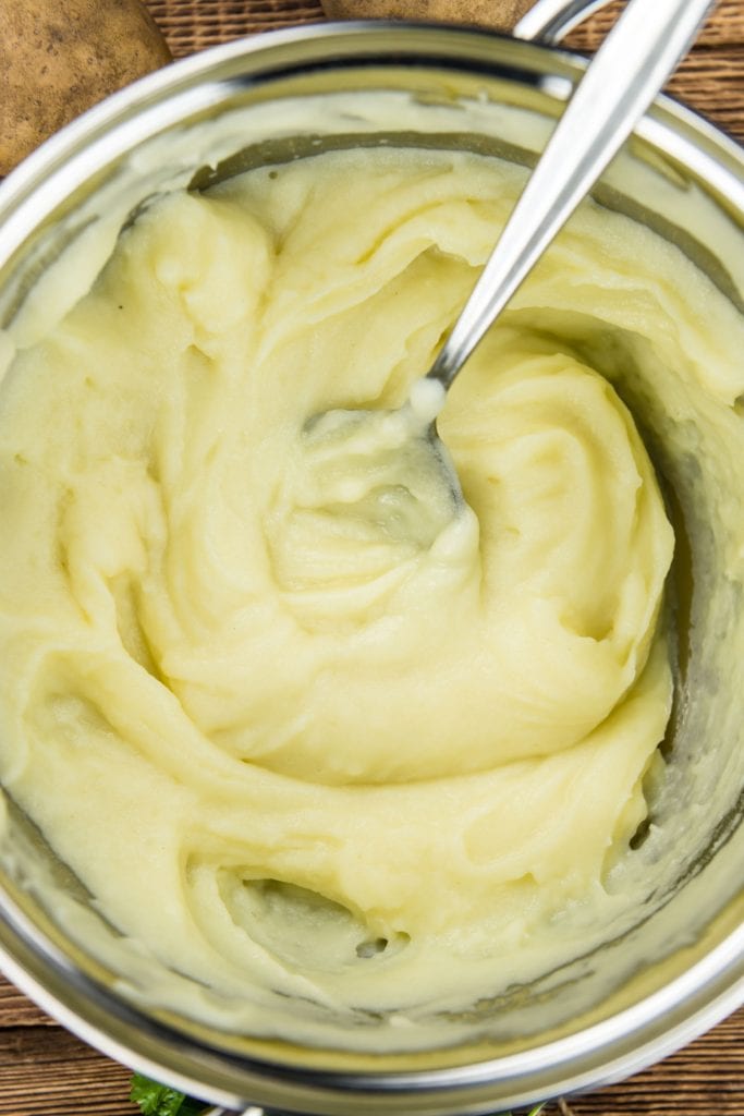 closeup of spoon in a pot of creamy mashed potatoes