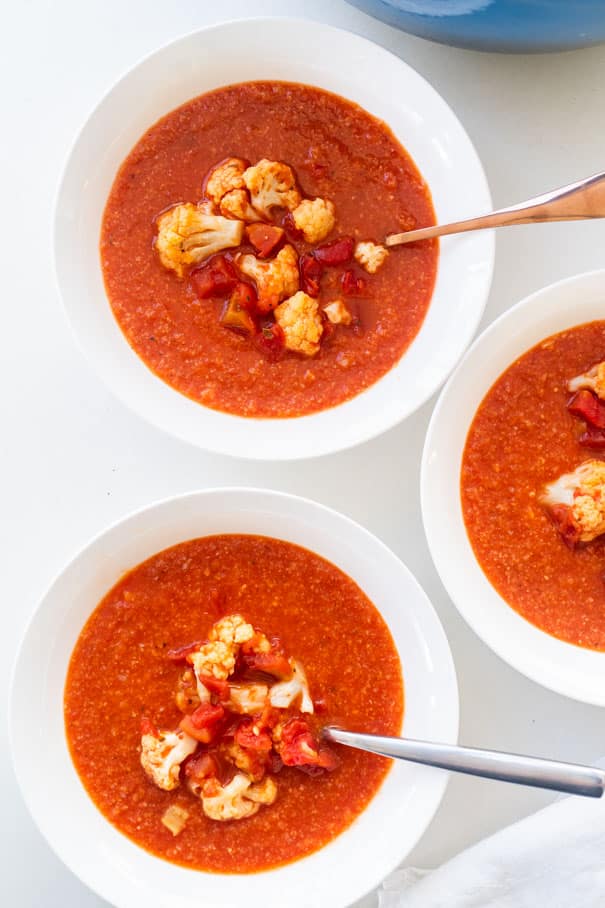 Easy to make creamy tomato soup with cauliflower recipe, ready in 35 minutes.  This homemade soup uses cans of crushed tomatoes and a whole head of cauliflower to make it a healthy dinner the entire family will love.  No milk needed.