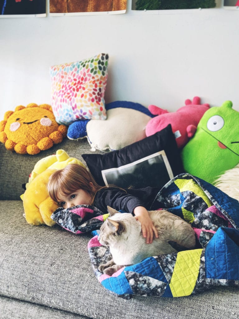 Toddler and cat cuddling on couch