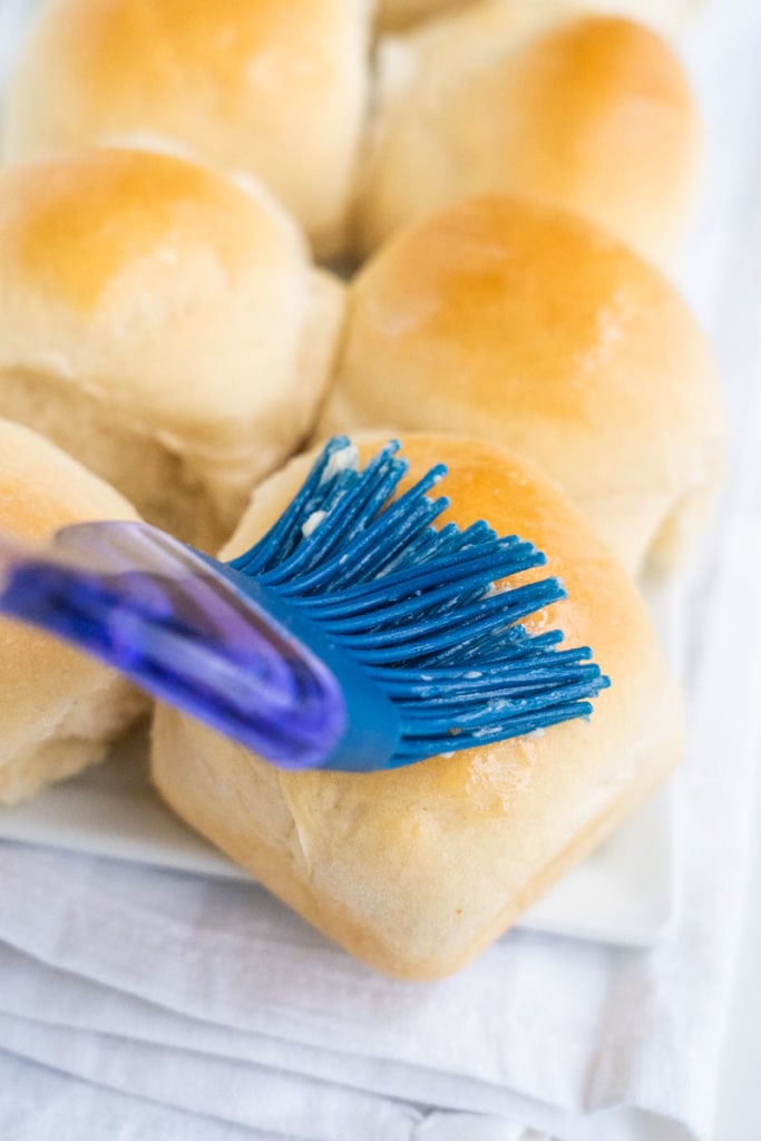 brush rubbing butter on rolls