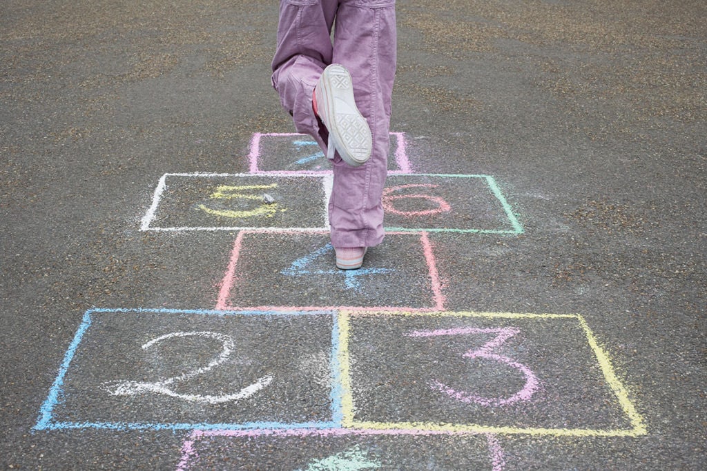 Little girl playing hopscotch outside