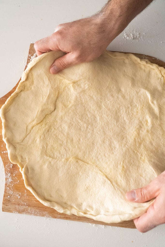hands stretching out pizza dough