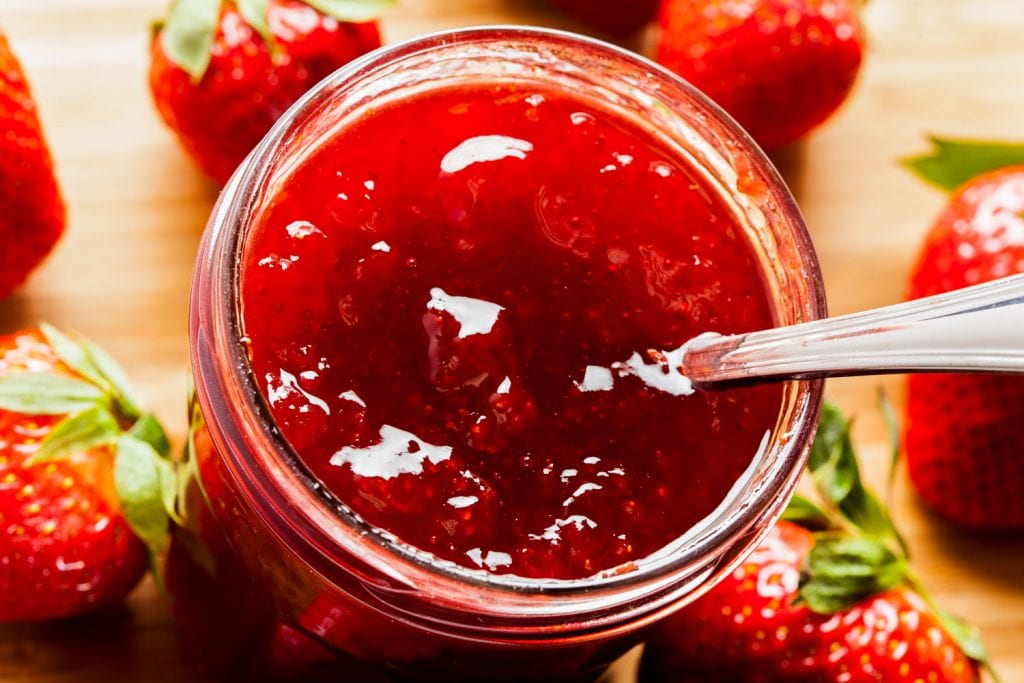 spoon going into mason jar of strawberry jam