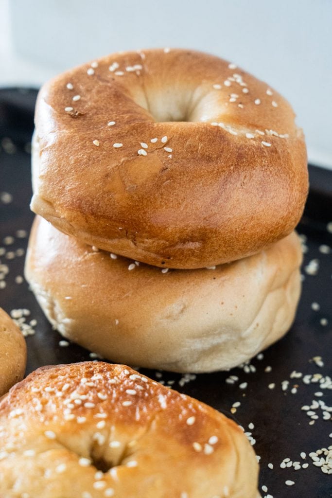 homemade bagels stacked on top of each other on cookie sheet