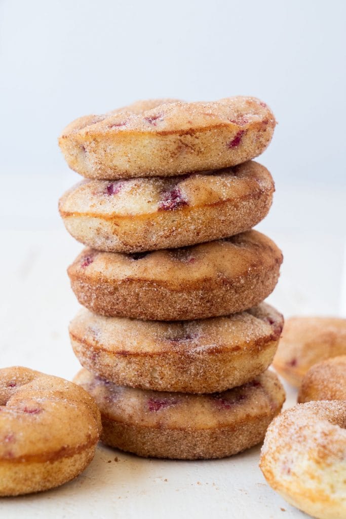 5 strawberry donuts covered in cinnamon sugar on top of each other on white table