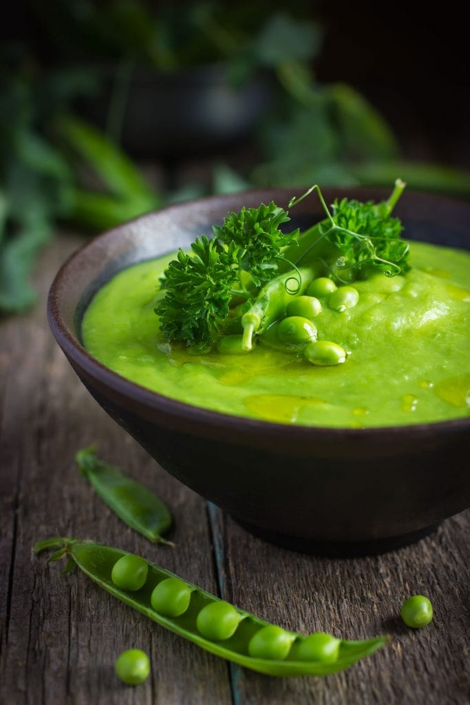 green cream of pea soup in brown bowl