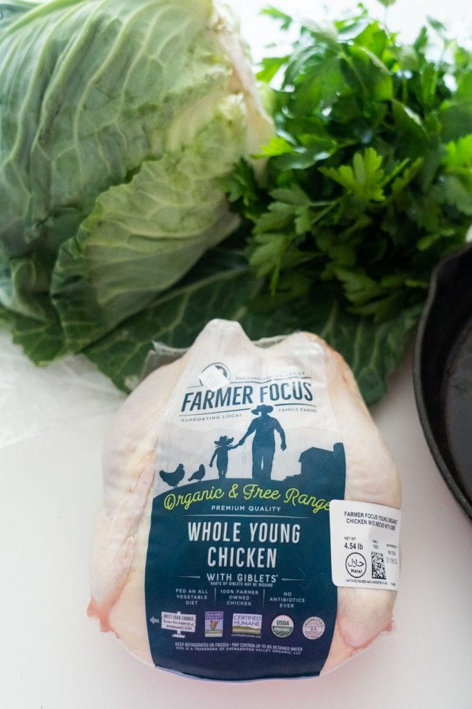 4 pound whole chicken in packaging with cabbage and parsley in kitchen