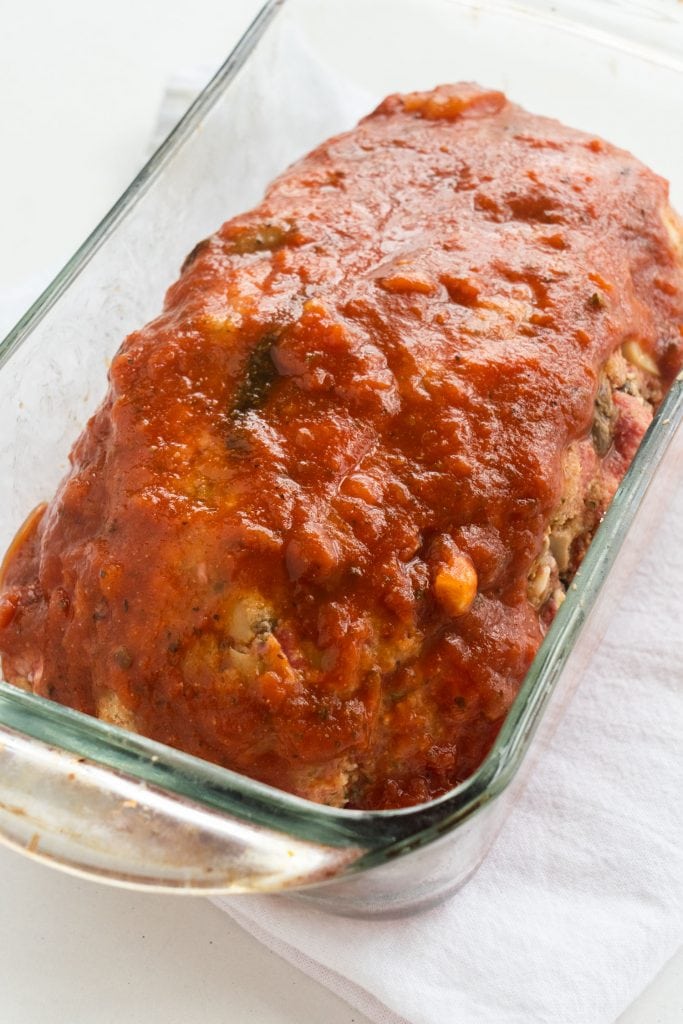tomato sauce poured on top of uncooked meatloaf in baking dish