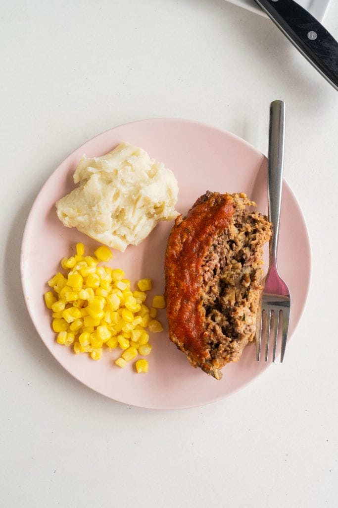 slice of meatloaf on plate with mashed potatoes and corn