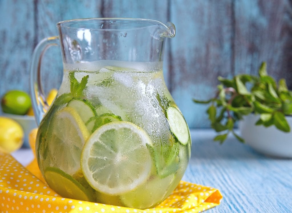 pitcher of ice water with sliced cucumbers and lemon