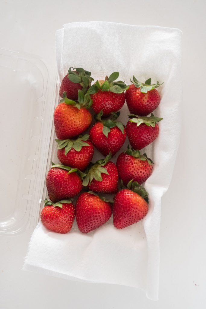 fresh strawberries on paper towel in plastic container
