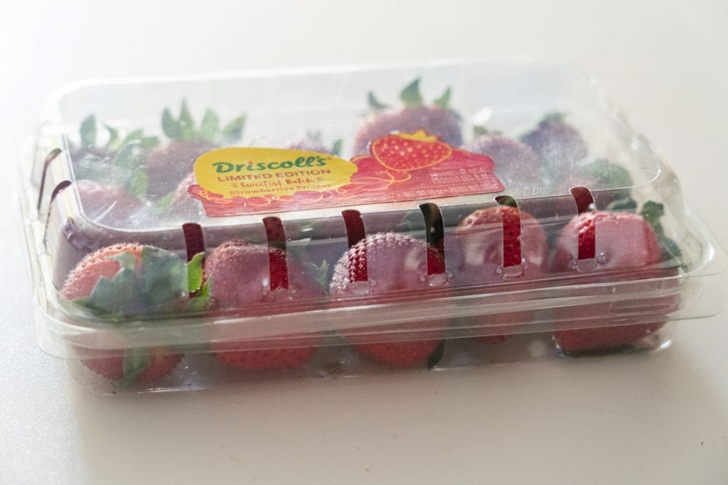 strawberries in plastic container on counter top