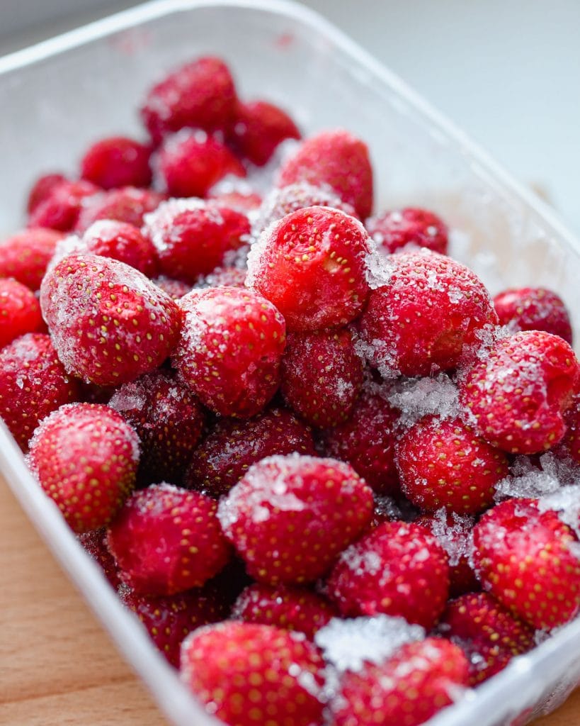 frozen strawberries with ice on them in freezer container