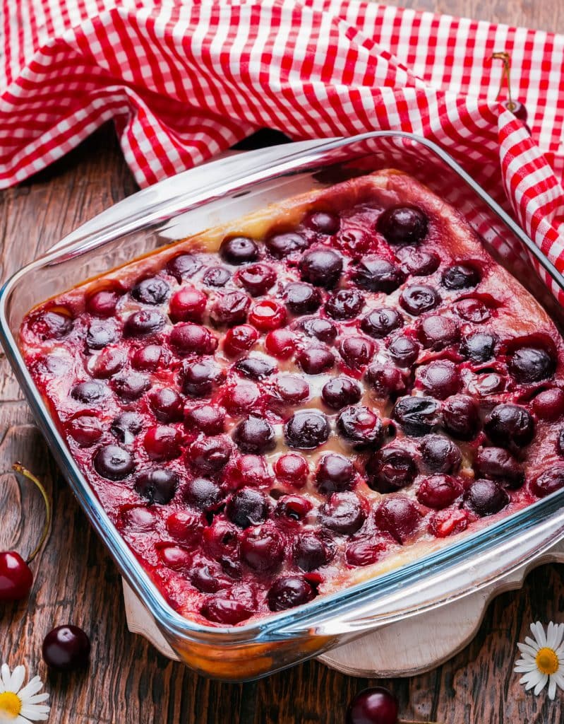 baked cherry clafoutis in a pan sitting on wooden background