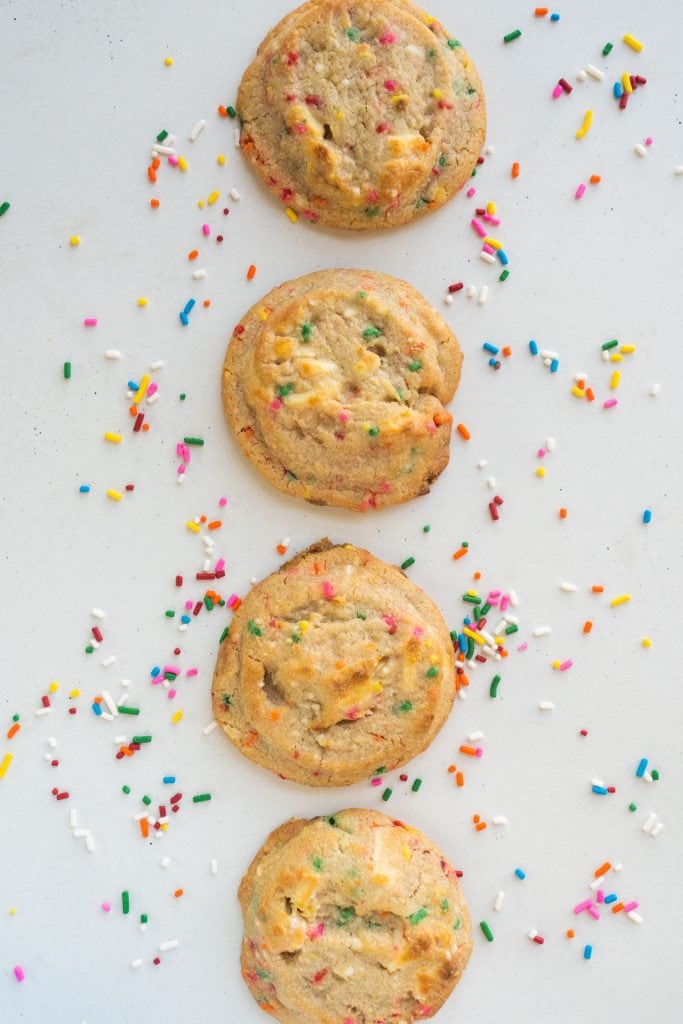 4 funfetti cookies with sprinkles on white table