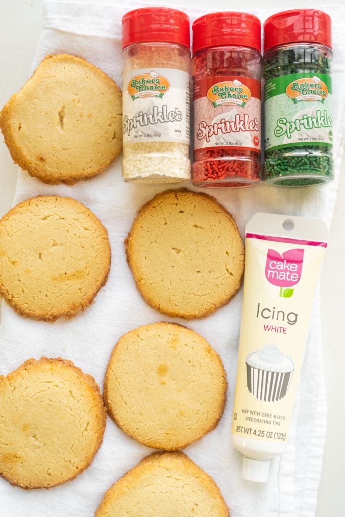 shortbread cookies with containers of sprinkles and a tube of white icing