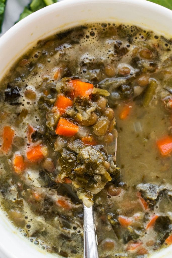 lentil kale soup with carrots in white bowl