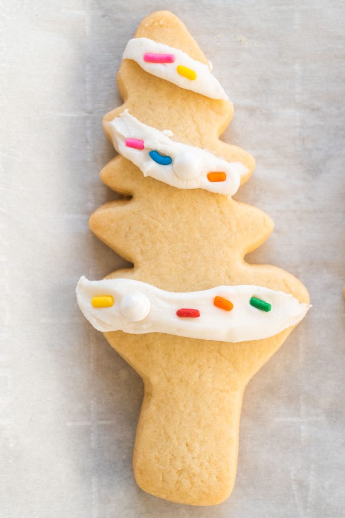 christmas tree cookie decorated with frosting for lights and rainbow sprinkles as light bulbs