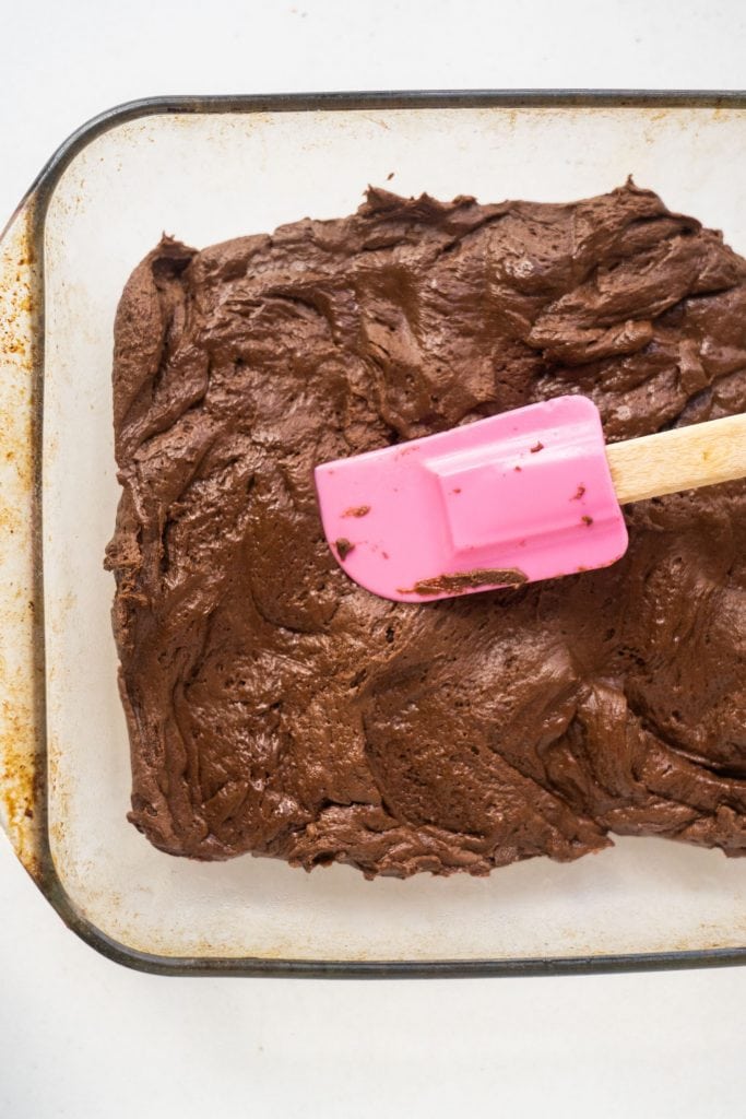 pink spatula patting down chocolate cake