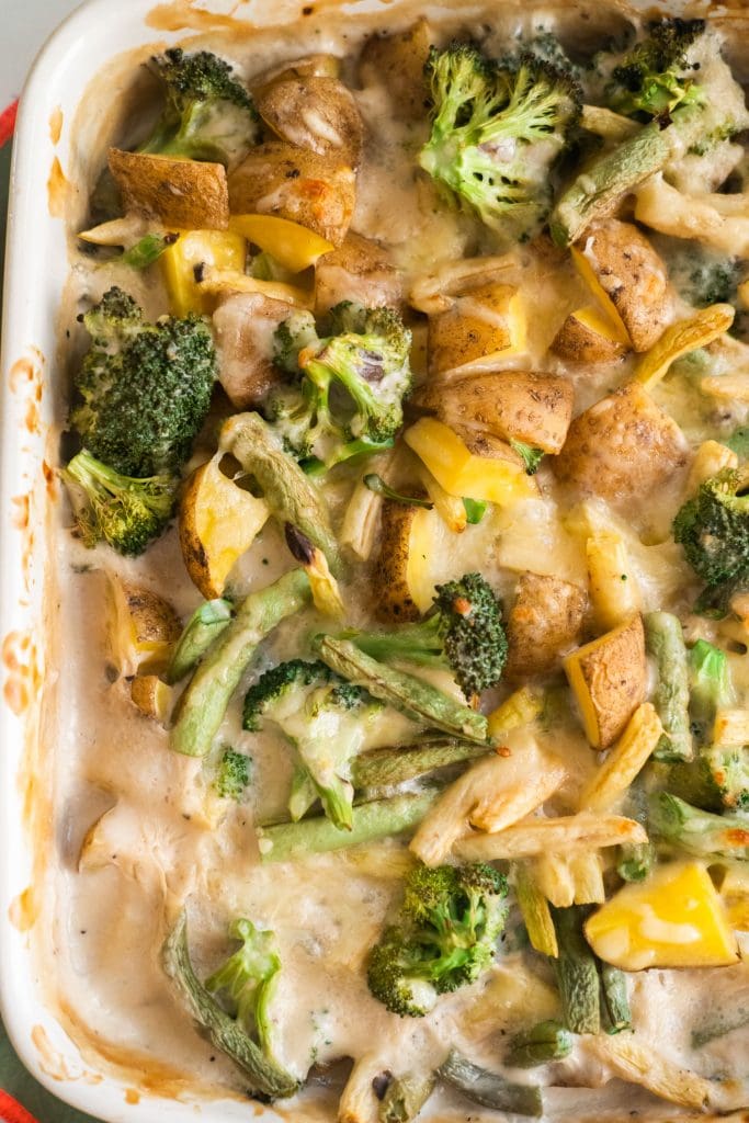 baking dish filled with baked green bean casserole with fresh beans, broccoli and potatoes in creamy sauce