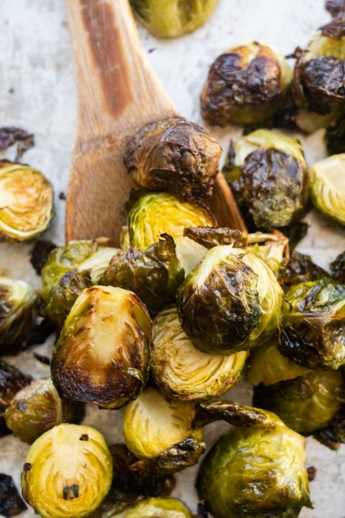 roasted brussels sprouts on baking sheet with wooden spoon