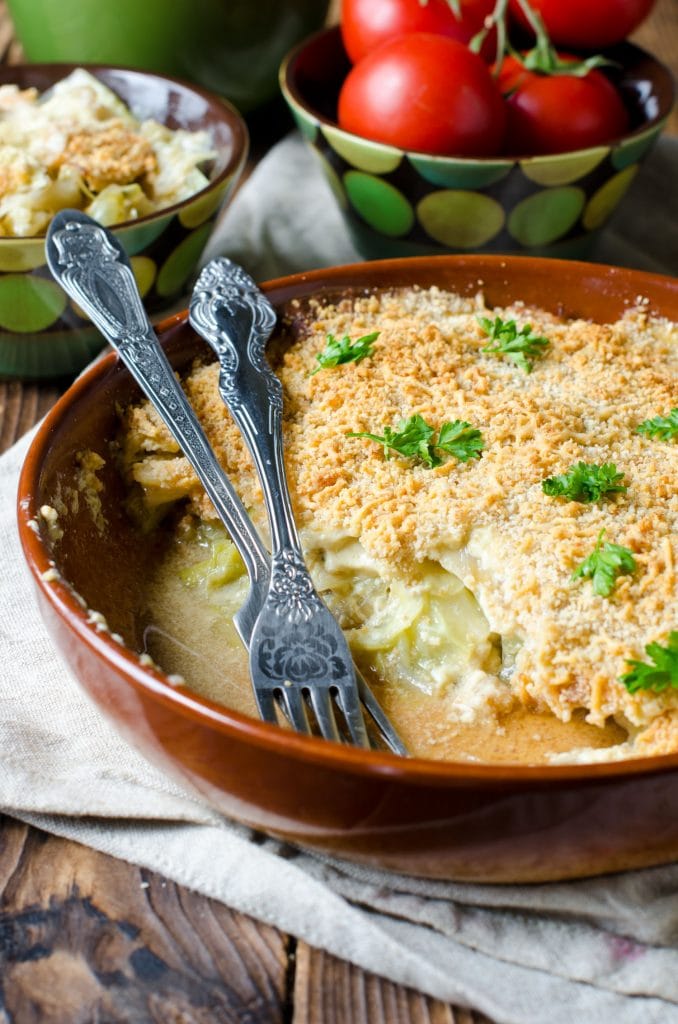 creamy cabbage casserole being spooned out of brown bowl on table