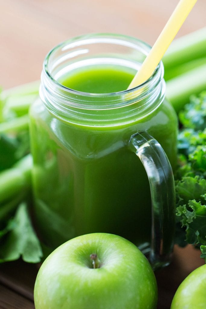 green juice in glass mason jar with yellow straw