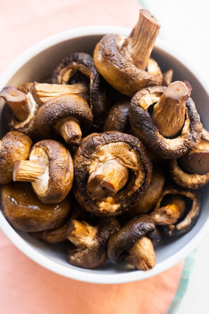 roasted mushrooms in white bowl on pink towel