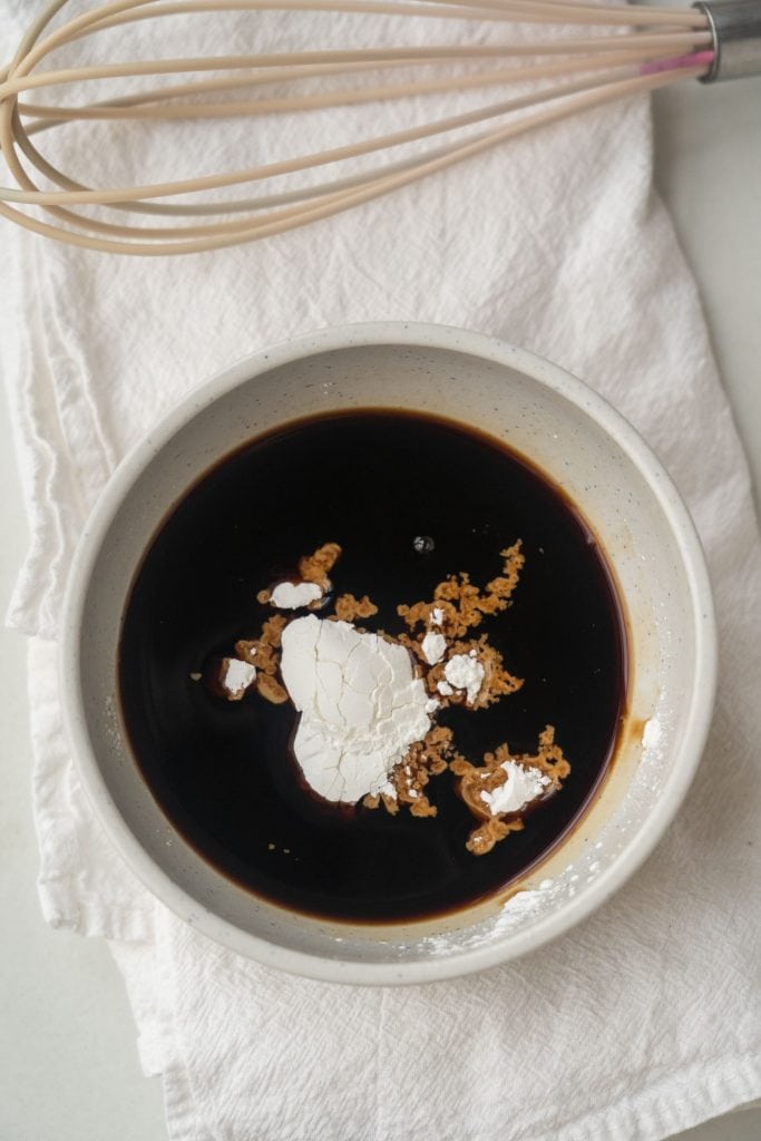 bowl filled with soy sauce and cornstarch with whisk nearby