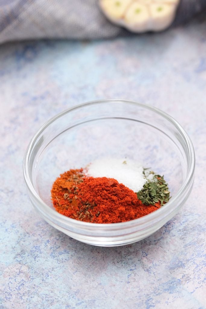 glass bowl with chili powder, cumin, paprika, oregano and salt