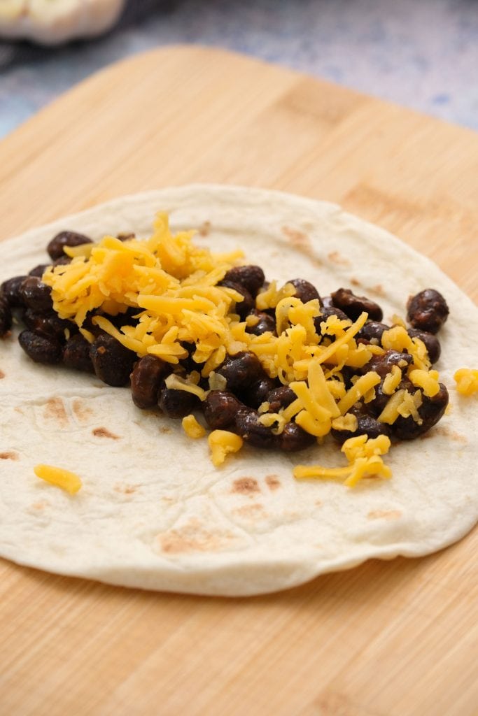 black beans on flour tortilla with shredded cheese on top