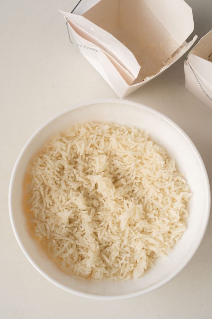 bowl filled with rice with empty rice takeout cartons.