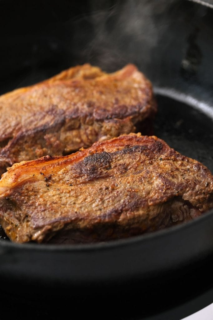 2 pieces of browned steak in skillet