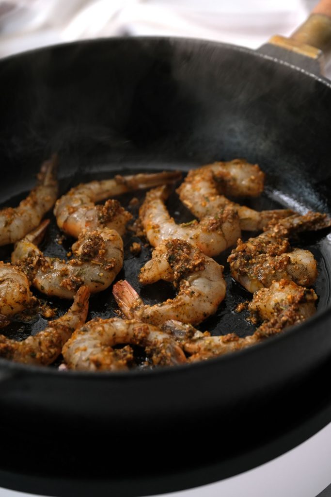 shrimp being cooked in skillet with marinade on top of them