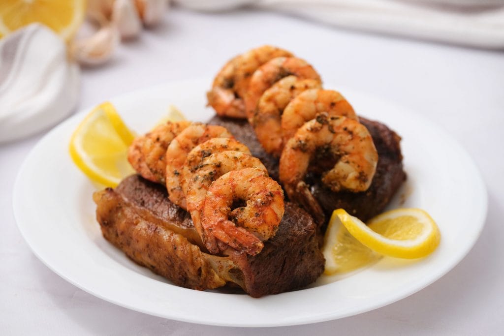 surf and turf with lemons on white plate