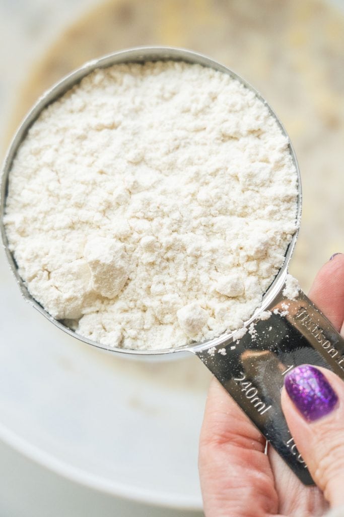 measuring cup filled with flour going into bowl. 