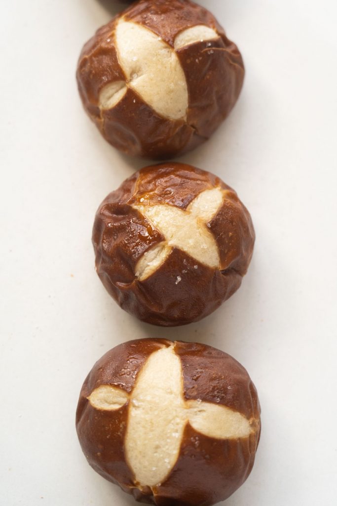 baked pretzel rolls on table with salt on top.