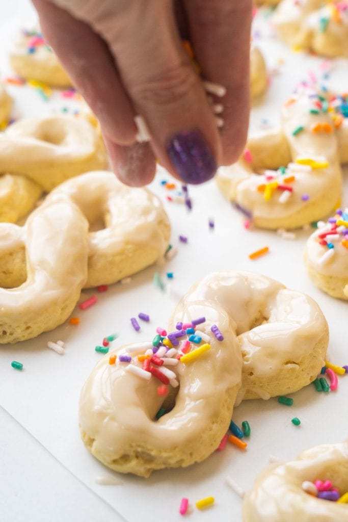 rainbow sprinkles being added on top of cookies. 