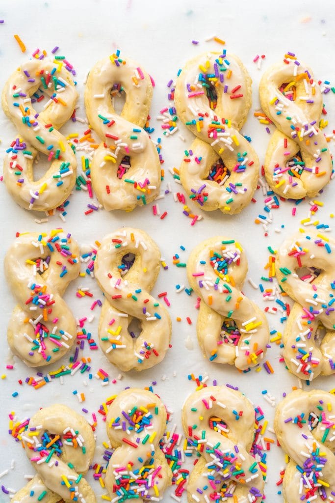 12 italian anise cookies with sprinkles on parchment paper.