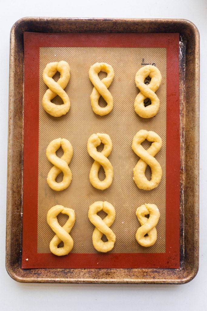 9 unbaked cookies on baking sheet with silicone baking mat.