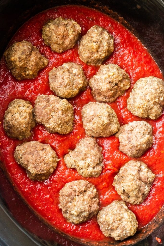 meatballs sitting in tomato sauce in slow cooker.