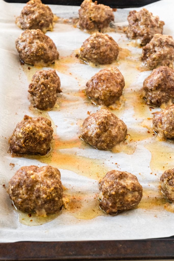 meatballs on baking sheet that have come out of the oven.