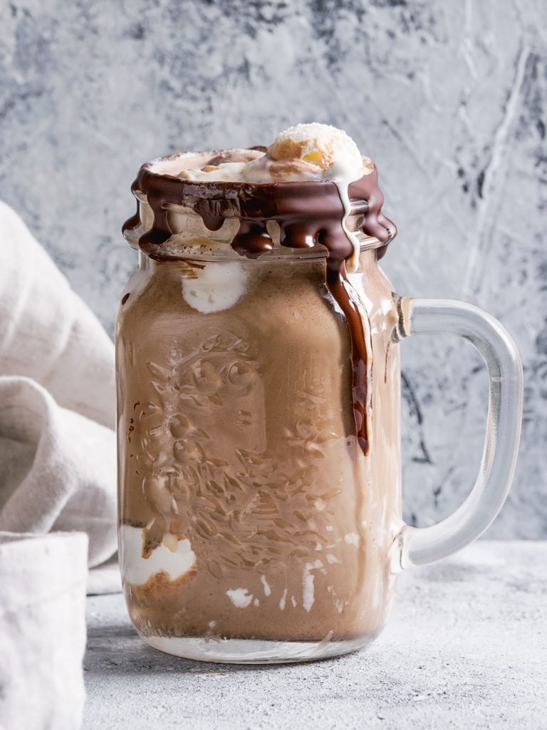 chocolate milk shake with hot fudge sauce and whipped cream in mug.