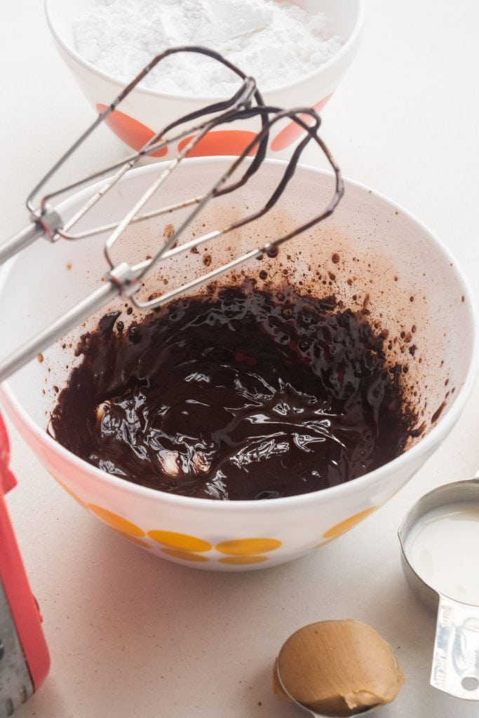 electric hand mixer mixing together butter and cocoa powder.