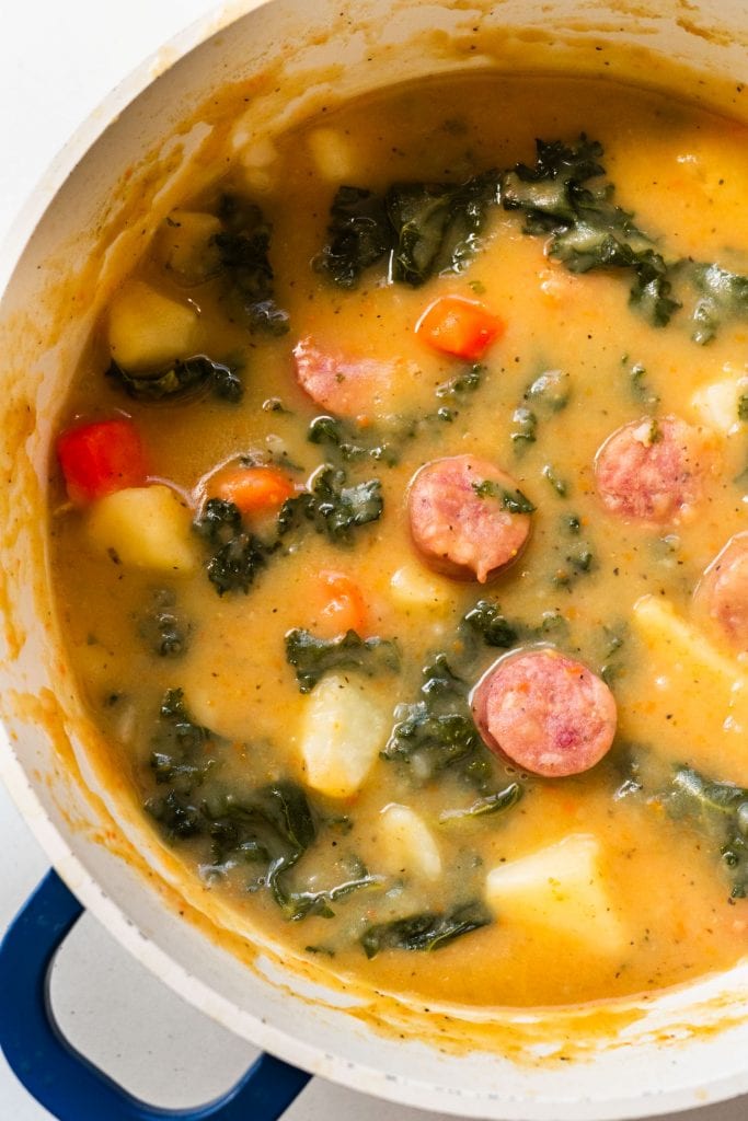 creamy sausage and kale soup in pot ready to be served.