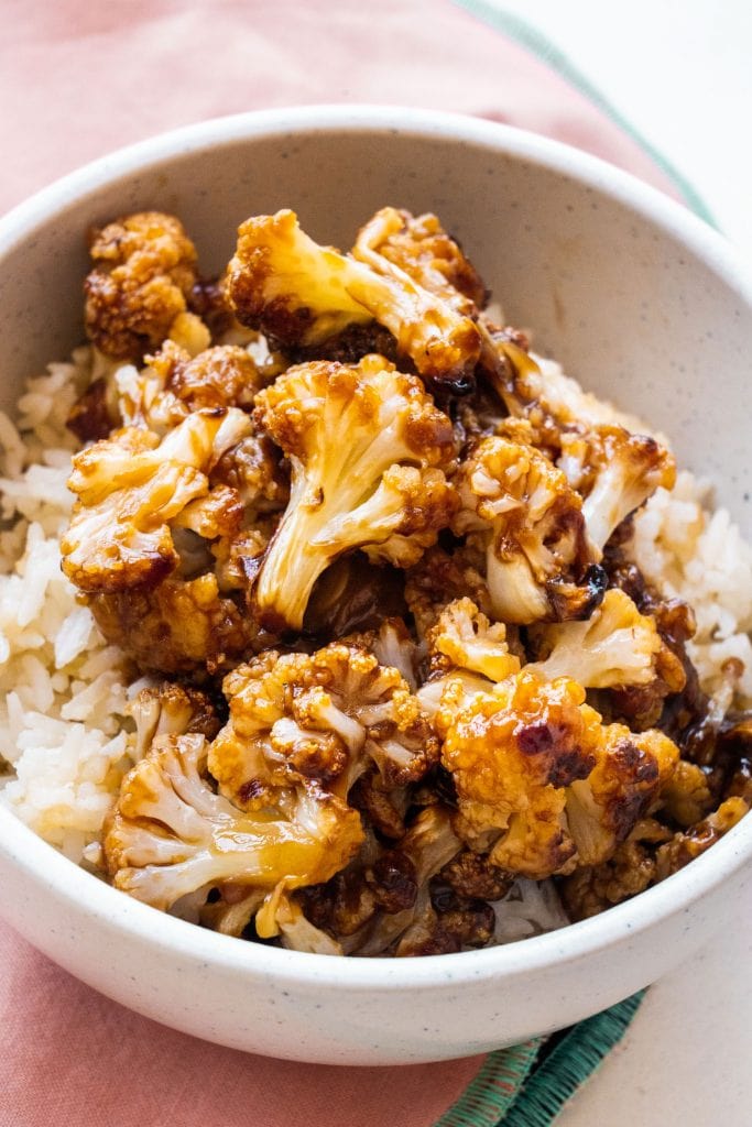 general tso's cauliflower on top of rice in bowl.