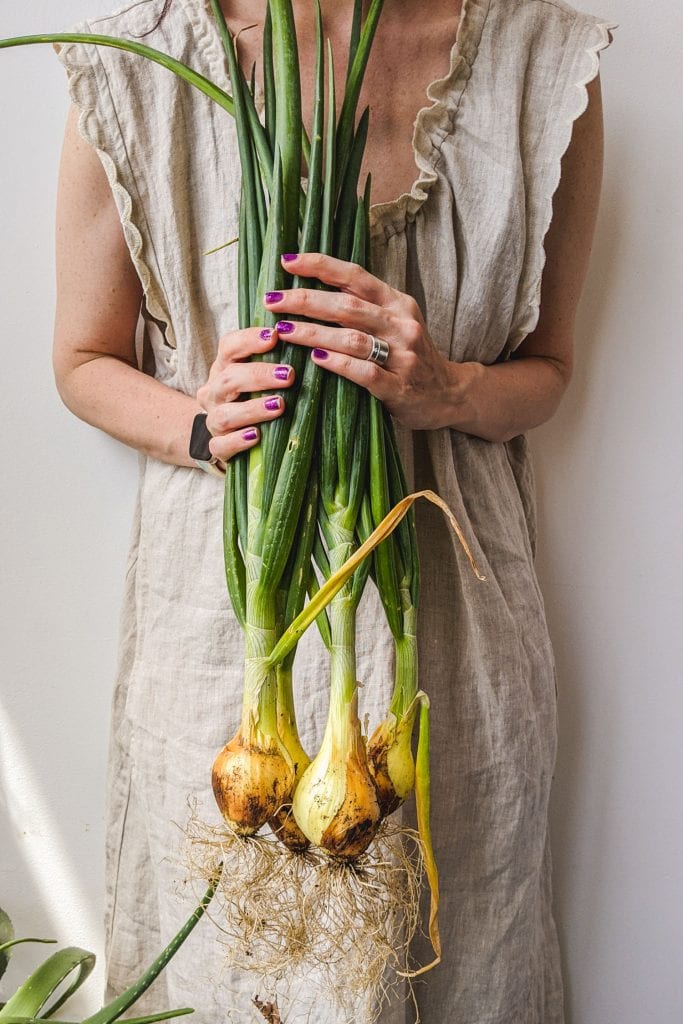 woman holding onions in linen dress