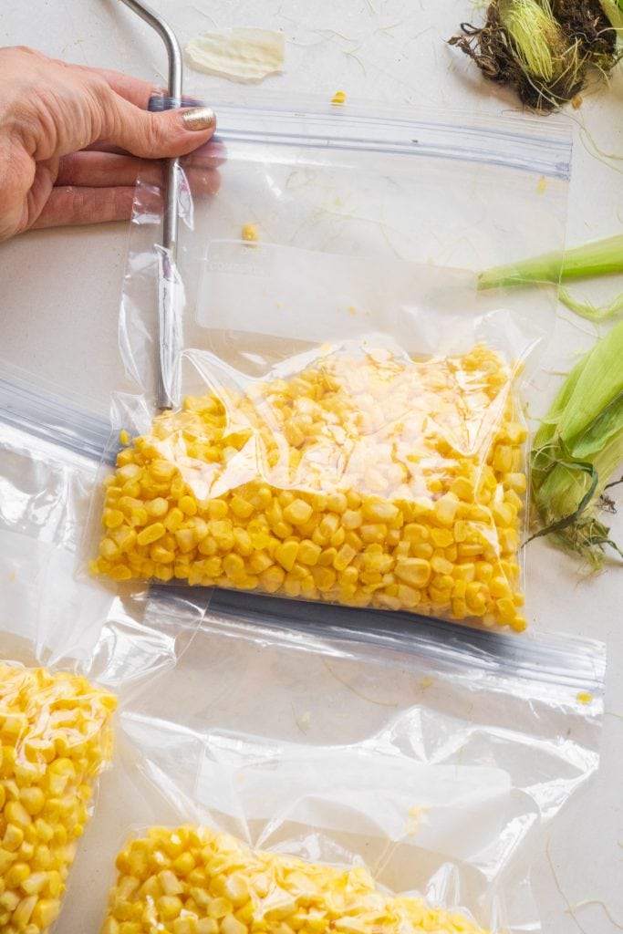 fresh corn packaged in freezer bags with straw sucking air out of them.