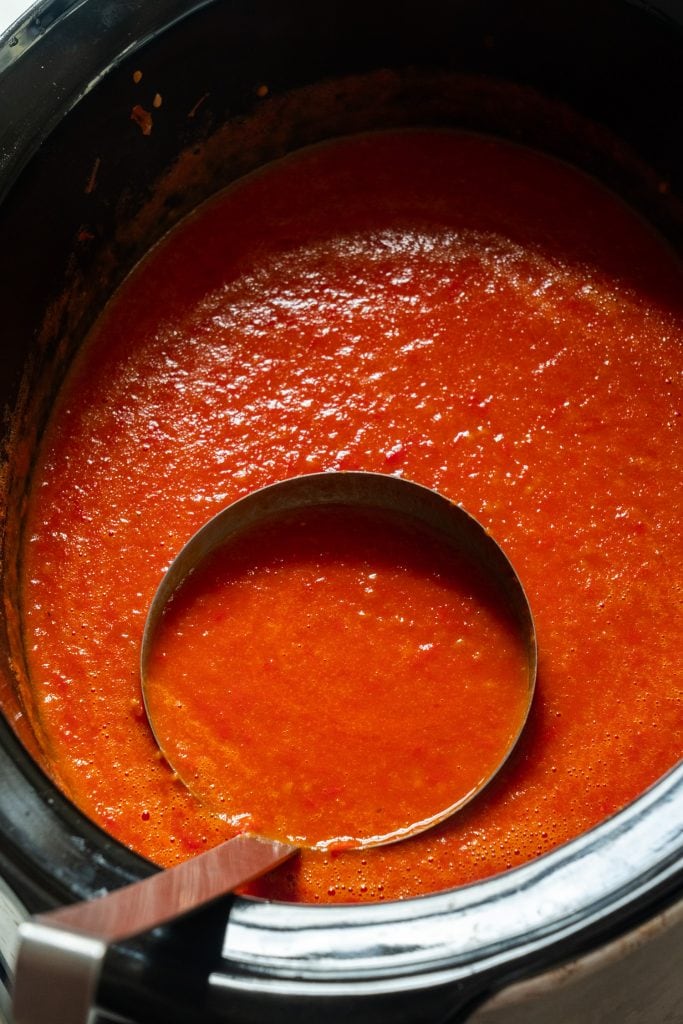 spoon filled with tomato sauce in crockpot.